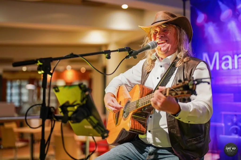 Mannie Live bei einem Live-Auftritt mit Akustikgitarre und Mikrofon