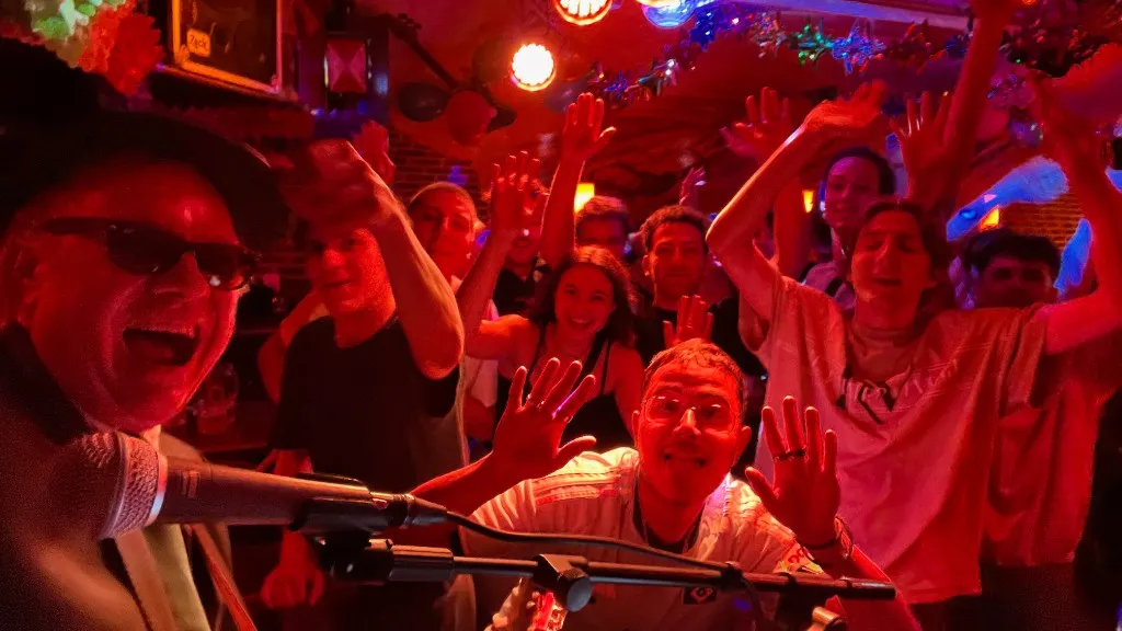 Mannie Live am Mikrofon, begeistertes Publikum mit erhobenen Händen in warmem Licht